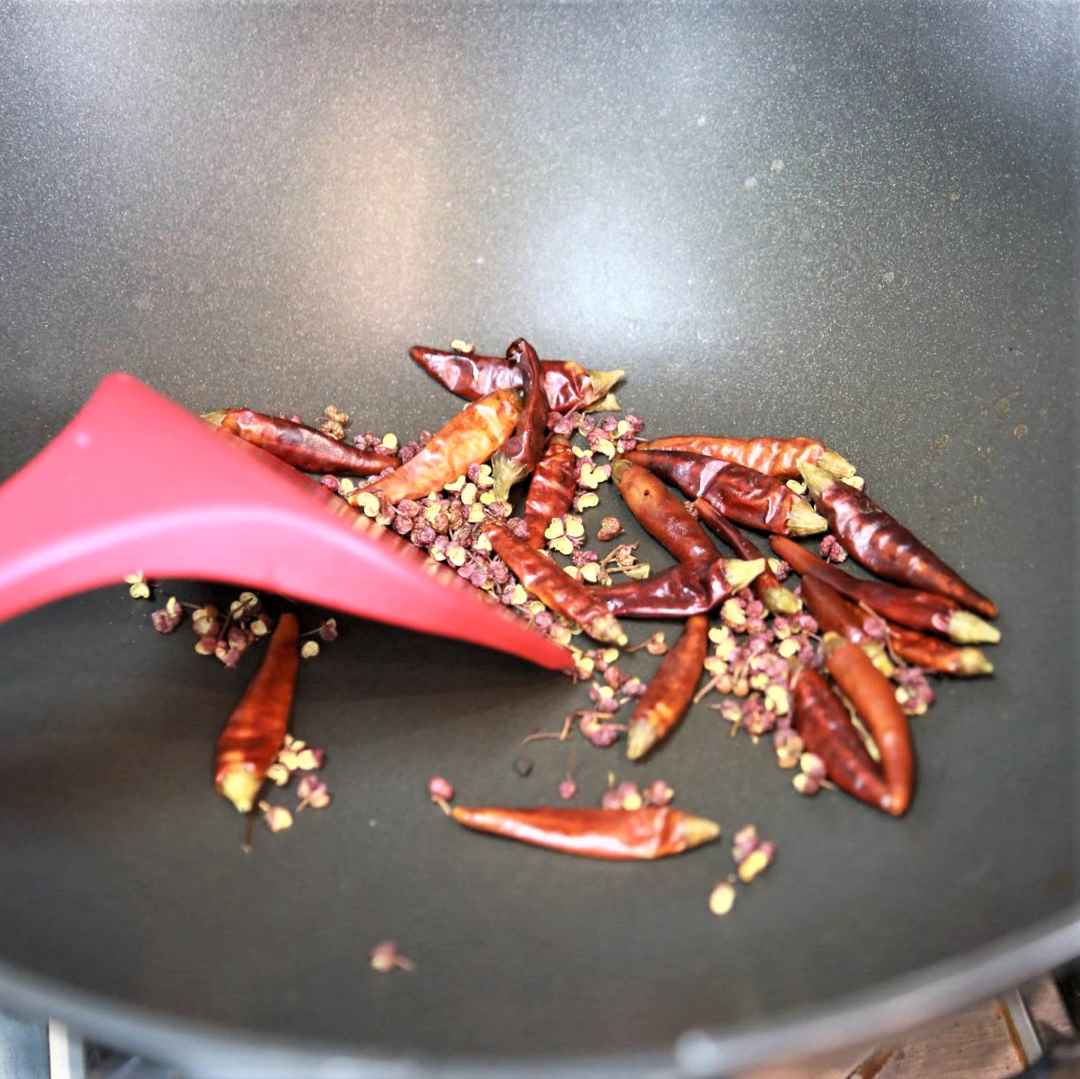 Stir-fry Sichuan peppercorns and dried chili over low heat until crispy.