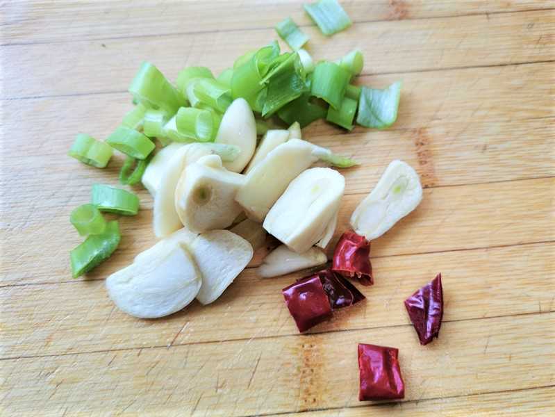 Cut green onions and dry red peppers. Peel and cut garlic into thin slices.